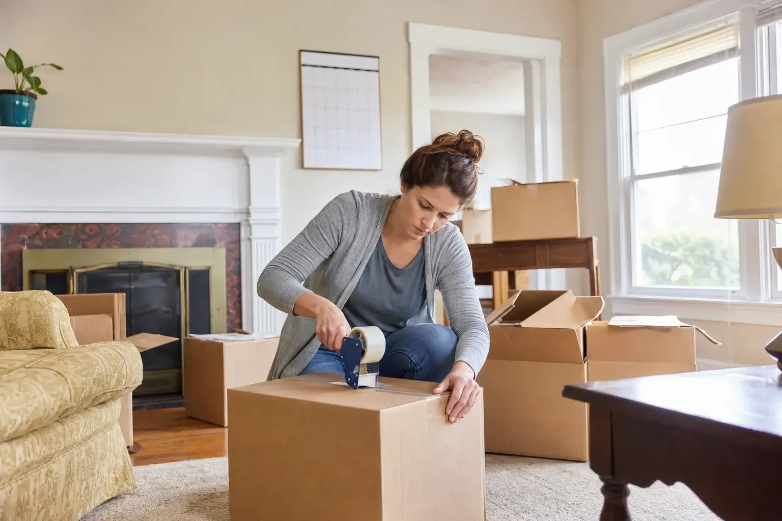 A person packing moving boxes in a dated living room