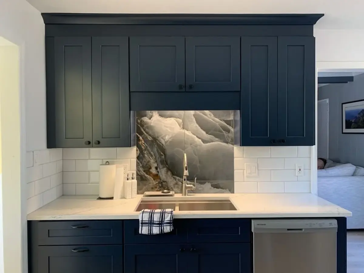 A finished kitchen with painted blue cabinetry, stone and subway-tile backsplash, and a white countertop