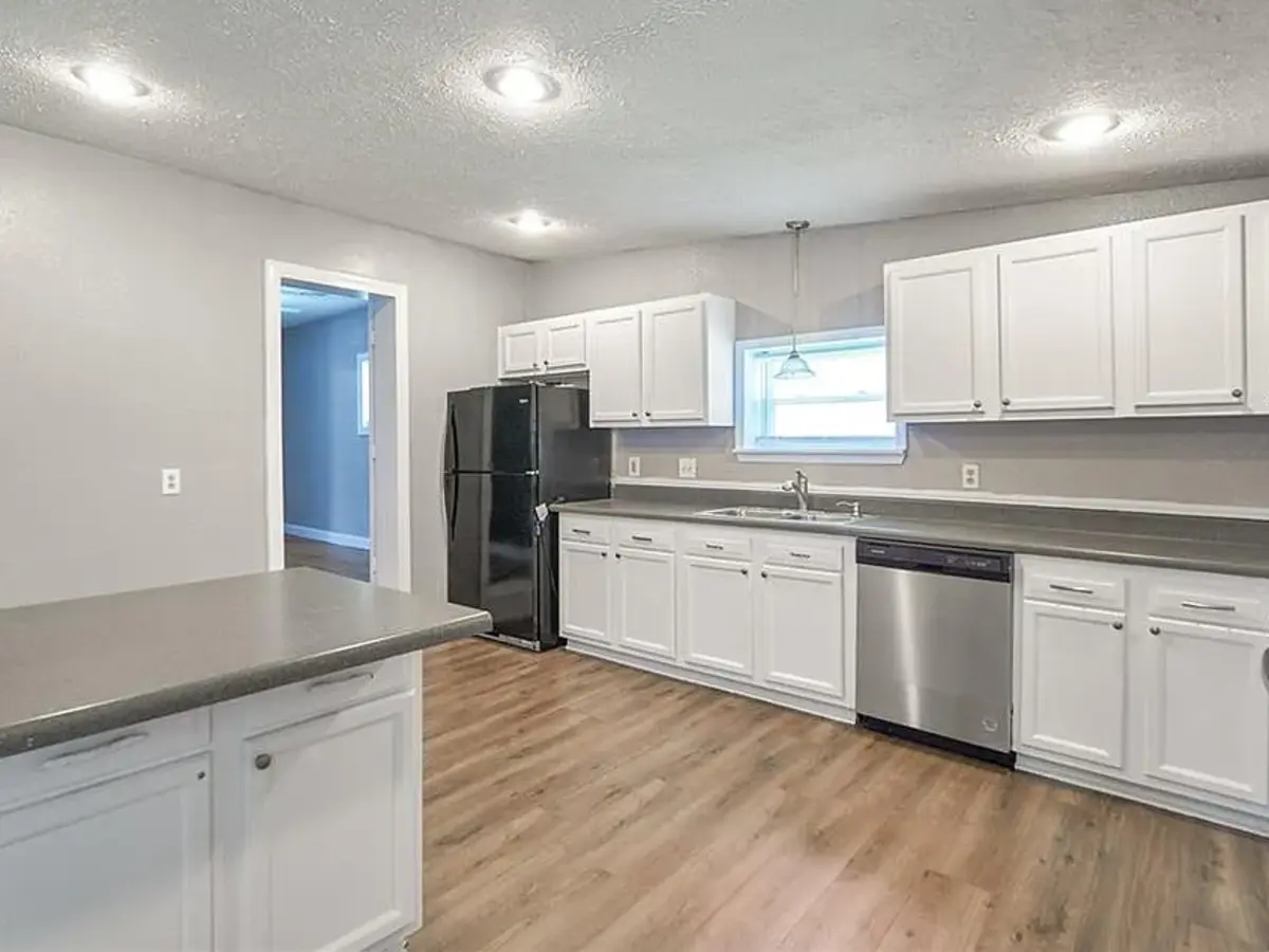 A completed kitchen with painted cabinets, new flooring, countertops, and appliances